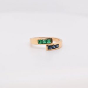 Minimalist 18K yellow gold ring adorned with square-cut natural emeralds and sapphires. Features 2x2 mm gemstones, with 3 emeralds and 3 sapphires. Size 5.75 US.