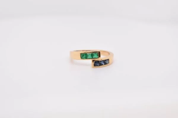 Minimalist 18K yellow gold ring adorned with square-cut natural emeralds and sapphires. Features 2x2 mm gemstones, with 3 emeralds and 3 sapphires. Size 5.75 US.