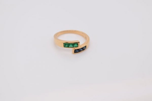 Minimalist 18K yellow gold ring adorned with square-cut natural emeralds and sapphires. Features 2x2 mm gemstones, with 3 emeralds and 3 sapphires. Size 5.75 US.