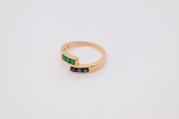 Minimalist 18K yellow gold ring adorned with square-cut natural emeralds and sapphires. Features 2x2 mm gemstones, with 3 emeralds and 3 sapphires. Size 5.75 US.