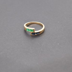 Minimalist 18K yellow gold ring adorned with square-cut natural emeralds and sapphires. Features 2x2 mm gemstones, with 3 emeralds and 3 sapphires. Size 5.75 US.