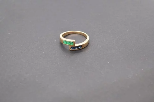 Minimalist 18K yellow gold ring adorned with square-cut natural emeralds and sapphires. Features 2x2 mm gemstones, with 3 emeralds and 3 sapphires. Size 5.75 US.